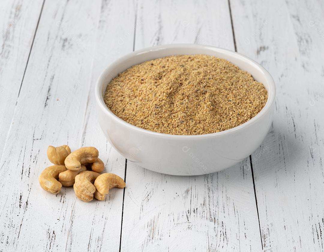 Farinha de castanha de caju em uma tigela sobre a mesa de madeira. Farinha sem glúten.