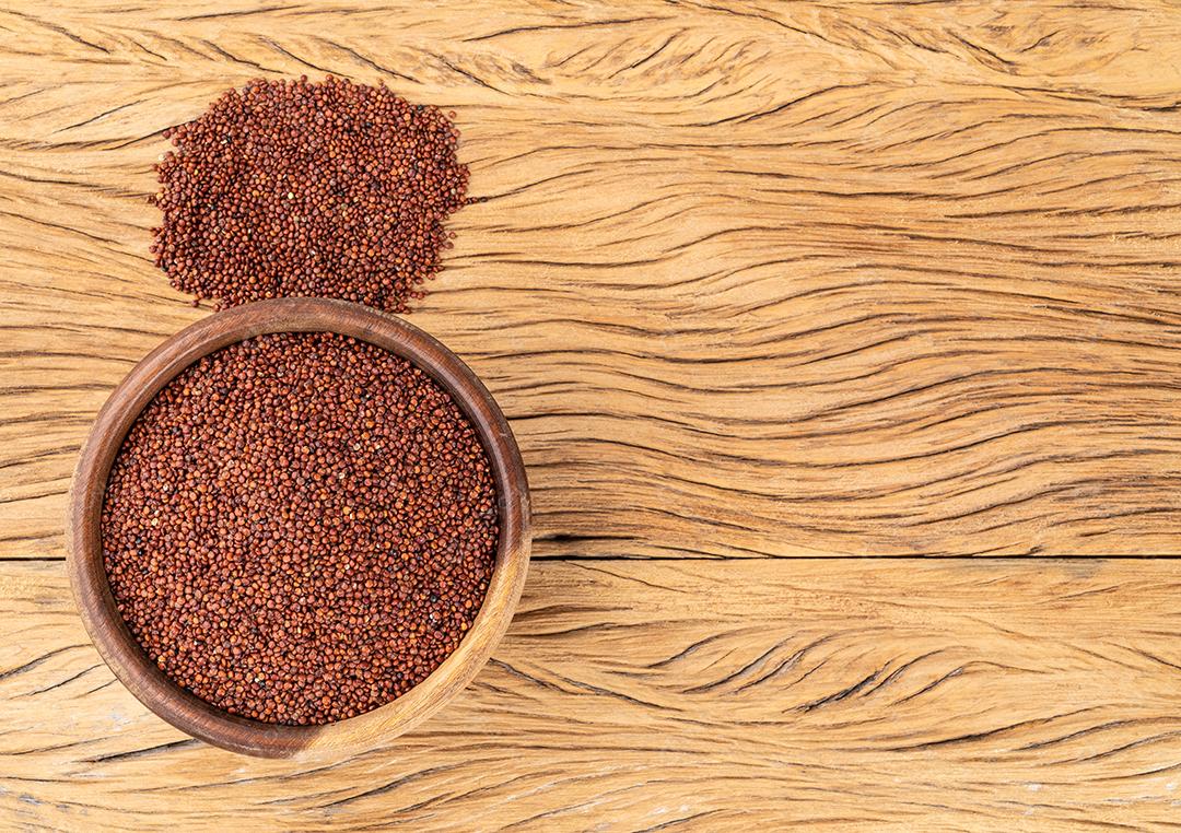 Quinoa vermelha crua em uma tigela sobre a mesa de madeira