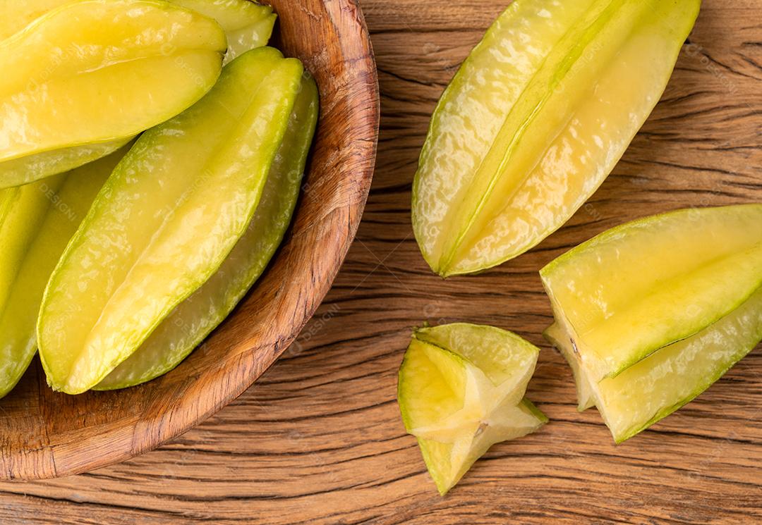 Carambolas com fatias em uma tigela sobre a mesa de madeira.