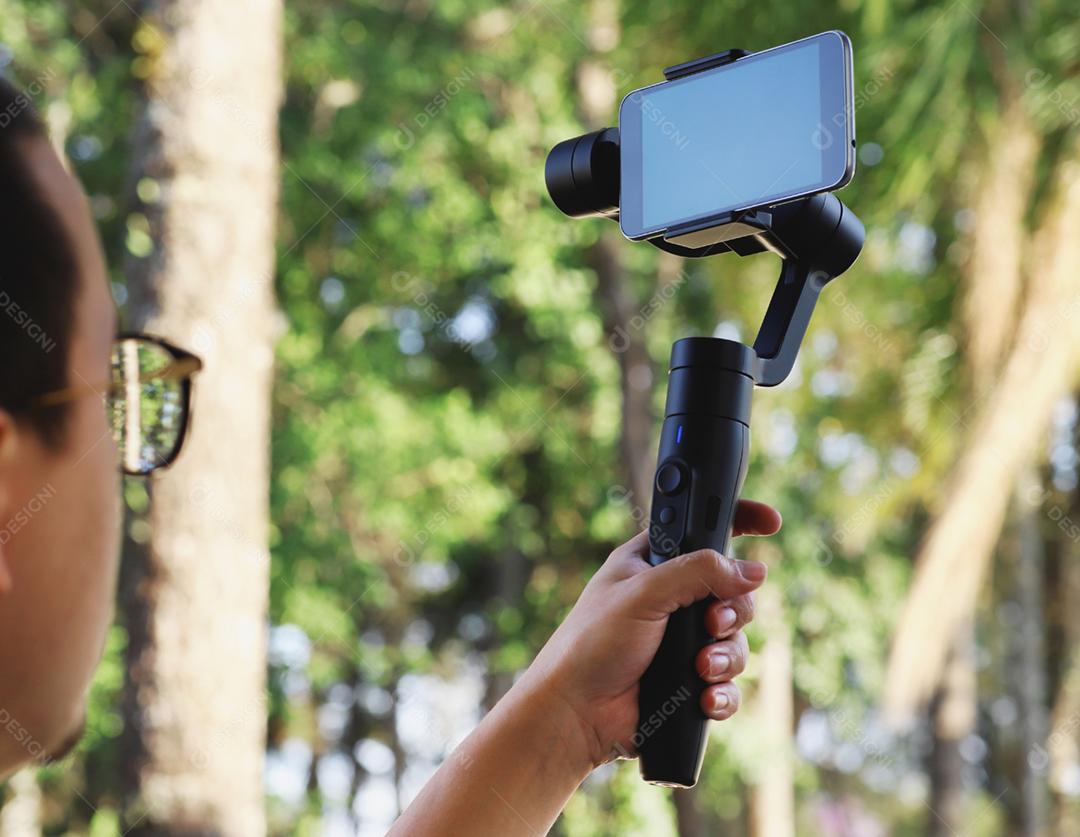Gimbal. Jovem usando estabilizador para celular e filmando th