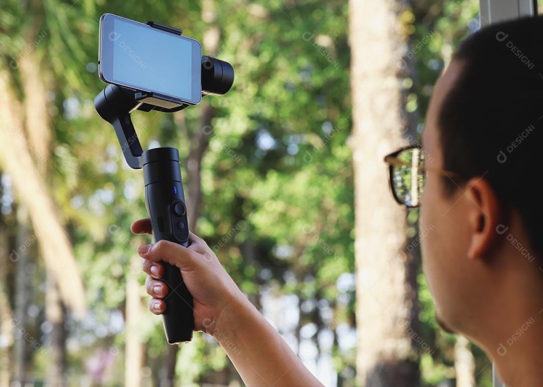 Gimbal. Jovem usando estabilizador para celular e filmando th