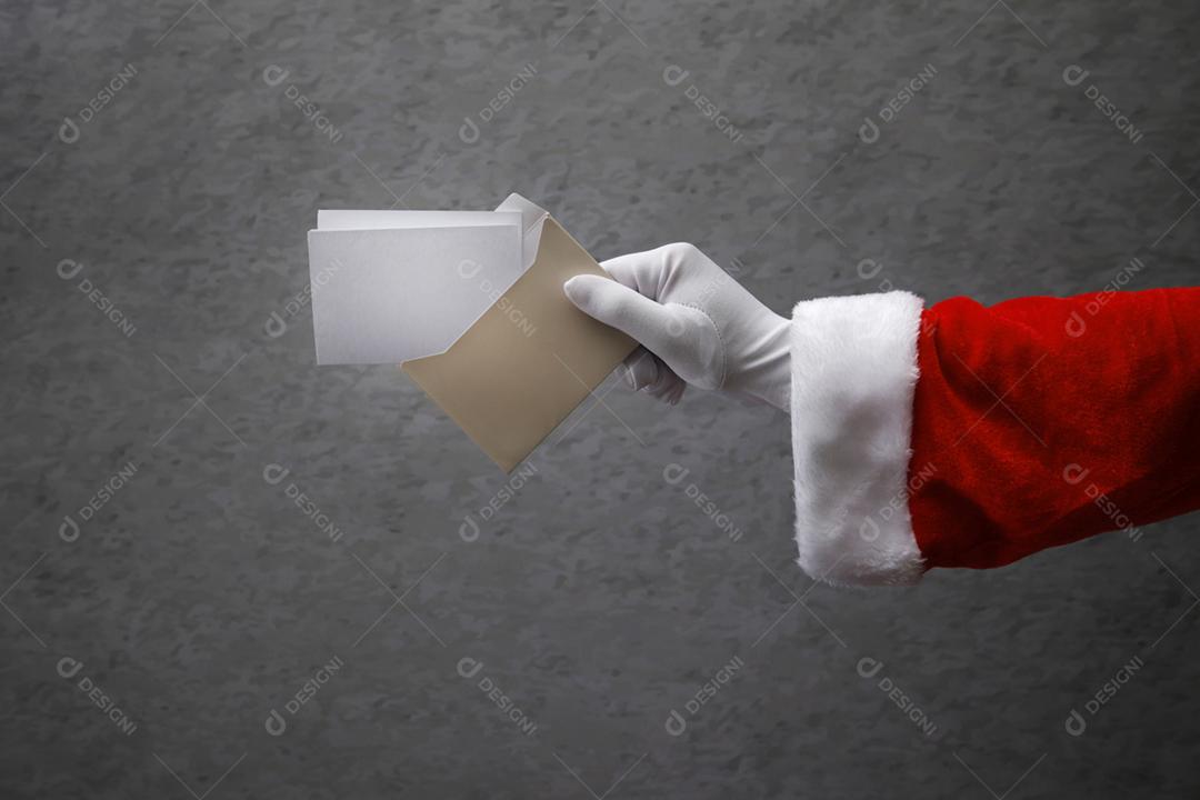 mão com luva de Papai Noel segurando envelope com carta