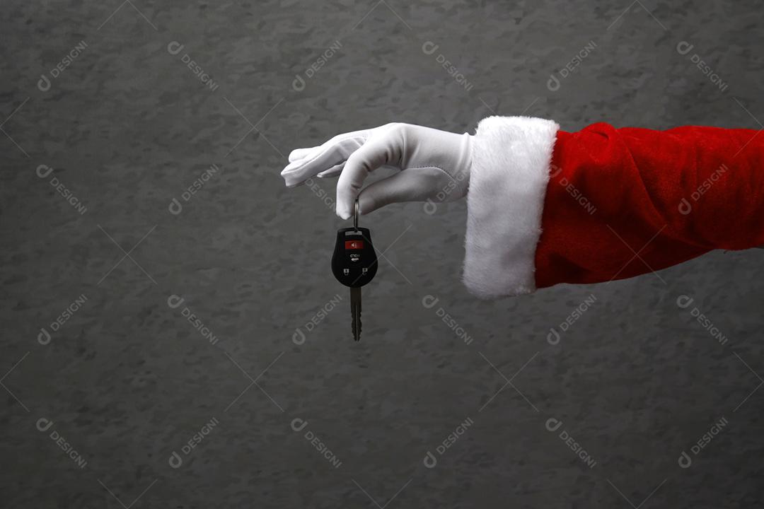 mão fechada com luva de Papai Noel segurando a chave do carro