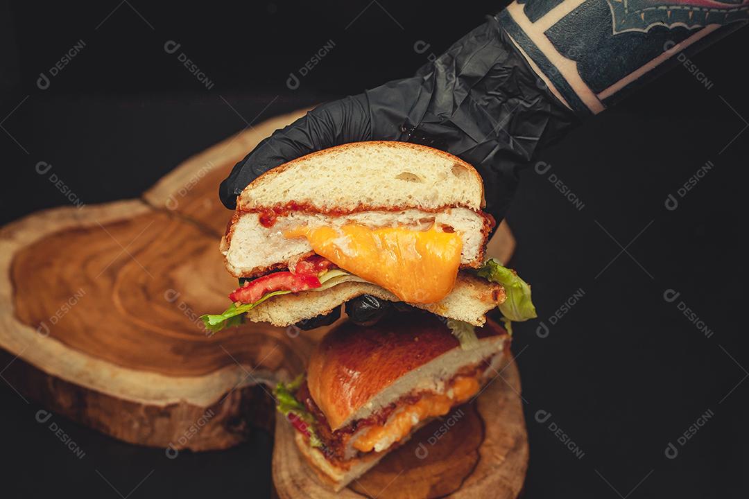 Homem segurando hambúrguer cortado ao meio