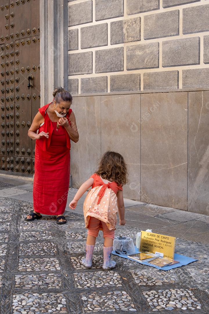 View of the beautiful little girl giving a coin to the street artist in Granada.