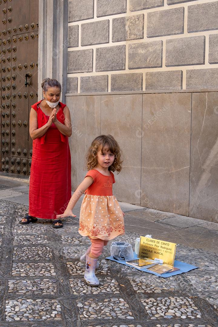 Vista da linda garotinha dando uma moeda ao artista de rua em Granada.
