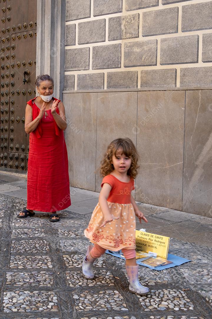 Vista da linda garotinha dando uma moeda ao artista de rua em Granada.