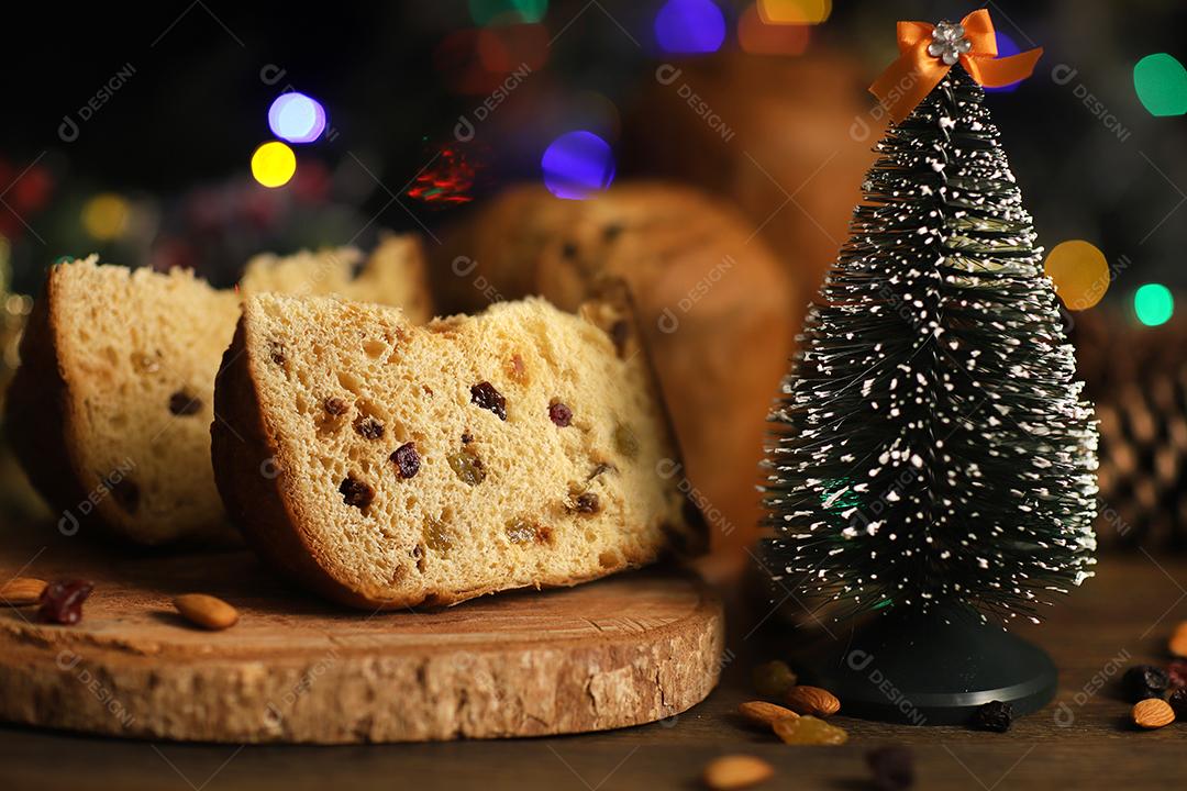 Deliciosa fatia de panetone com frutas cristalizadas em cima da mesa em um fundo desfocado.