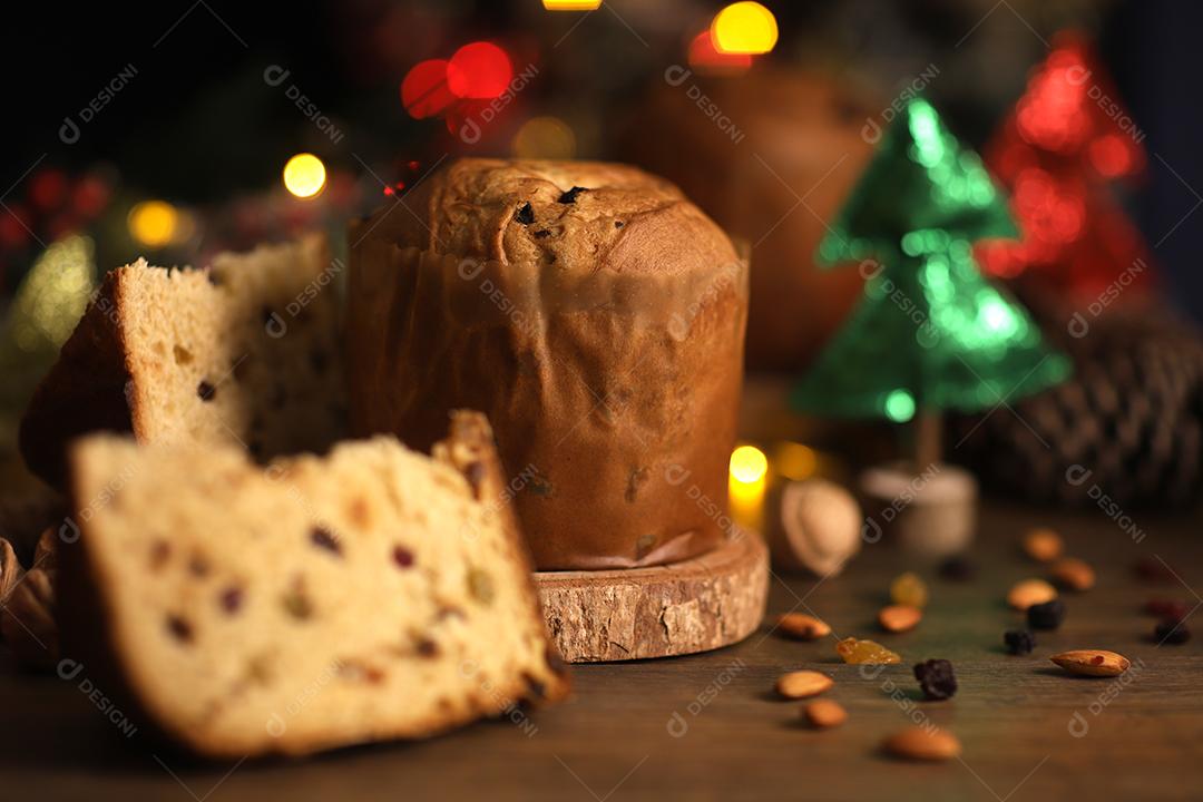 Deliciosa fatia de panetone com frutas cristalizadas em cima da mesa em um fundo desfocado.