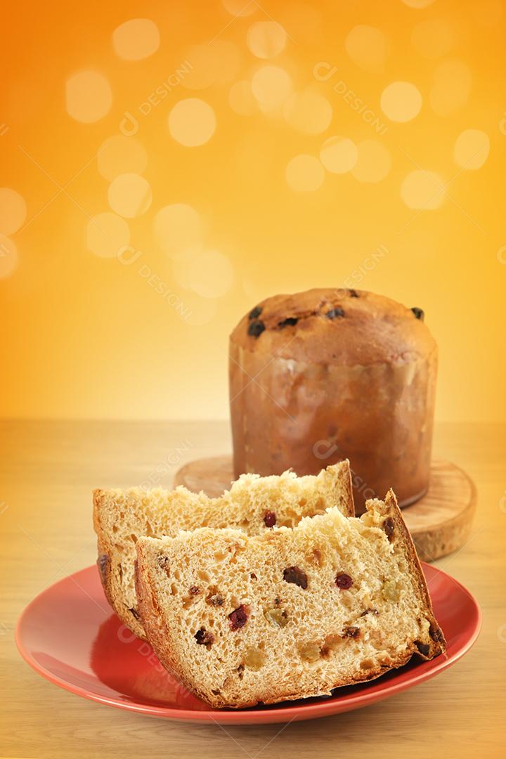 Deliciosa fatia de panetone com frutas cristalizadas em cima da mesa em um fundo desfocado.