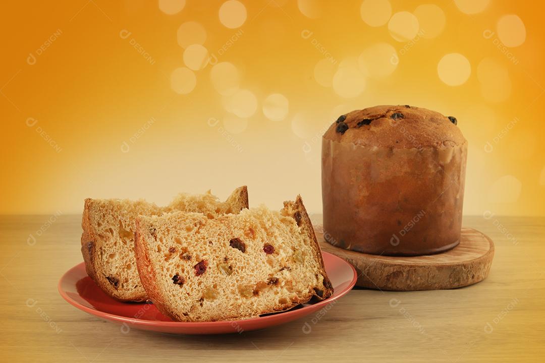 Deliciosa fatia de panetone com frutas cristalizadas em cima da mesa em um fundo desfocado.