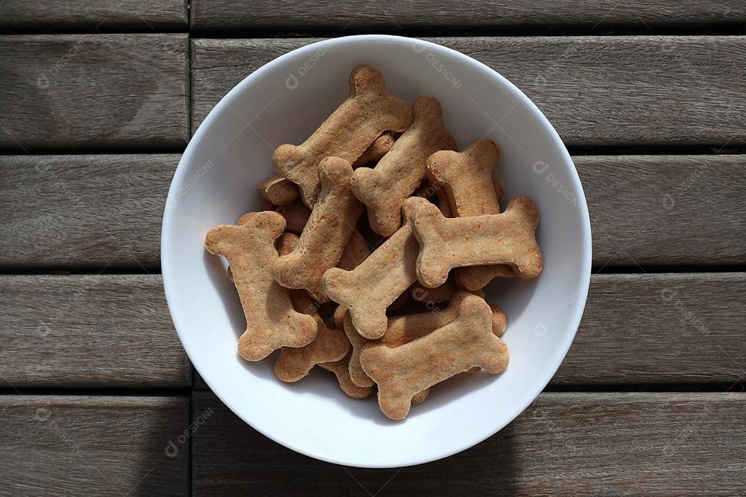 comida de cachorro seca em uma tigela na vista superior de fundo de madeira.