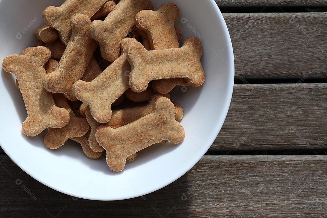 comida de cachorro seca e água na tigela na vista superior de fundo de madeira.