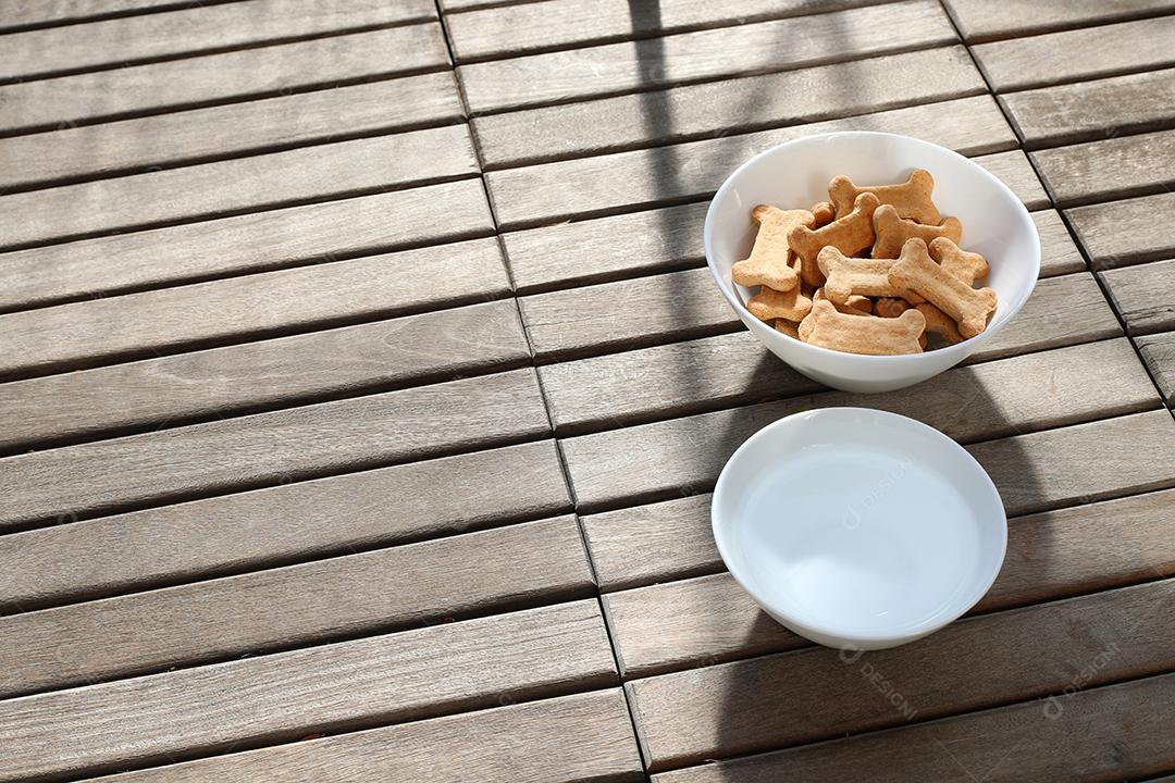 comida de cachorro seca e água na tigela na vista superior de fundo de madeira.