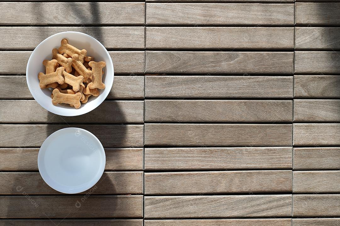 comida de cachorro seca e água na tigela na vista superior de fundo de madeira.