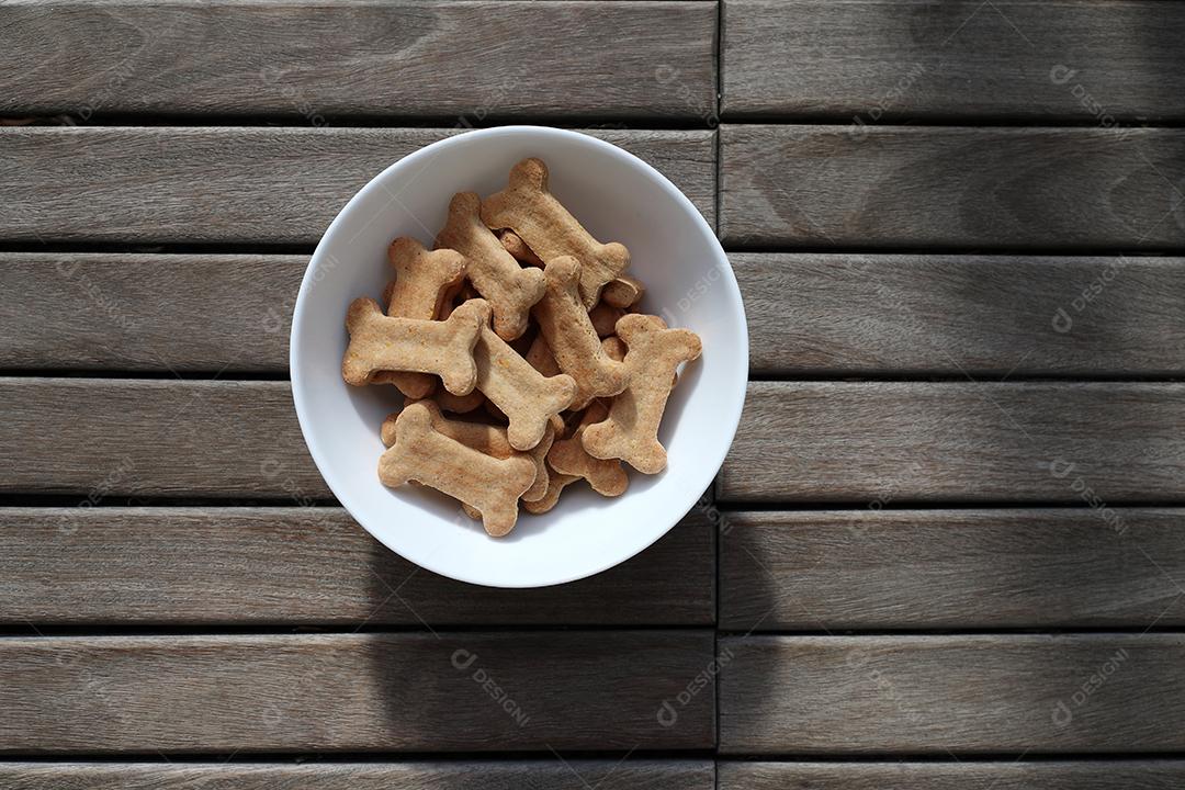 comida de cachorro seca em uma tigela na vista superior de fundo de madeira.