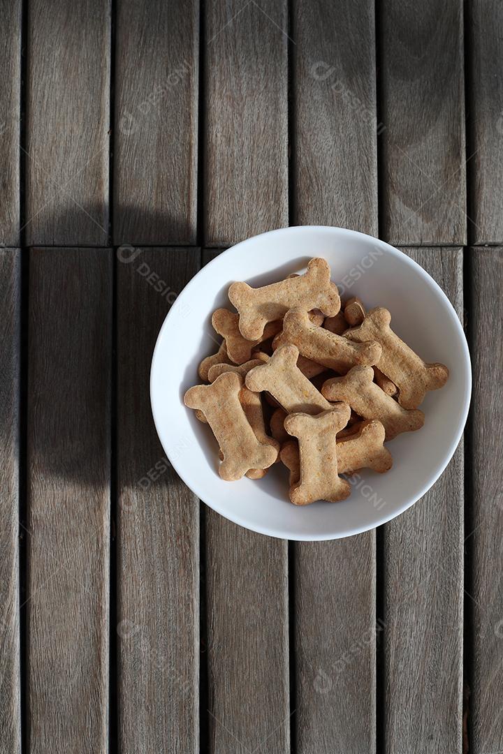 comida de cachorro seca em uma tigela na vista superior de fundo de madeira.