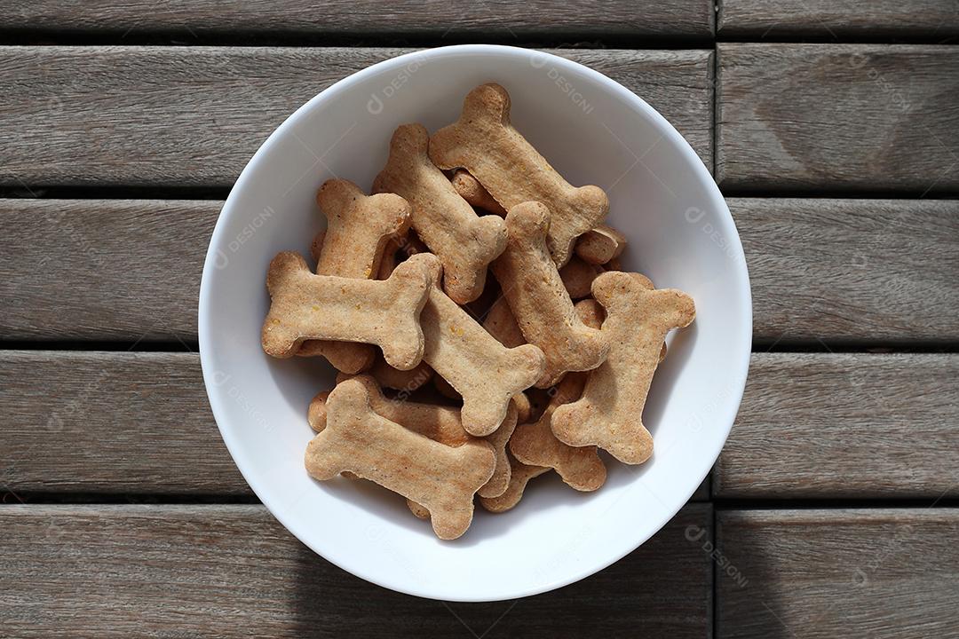 comida de cachorro seca em uma tigela na vista superior de fundo de madeira.