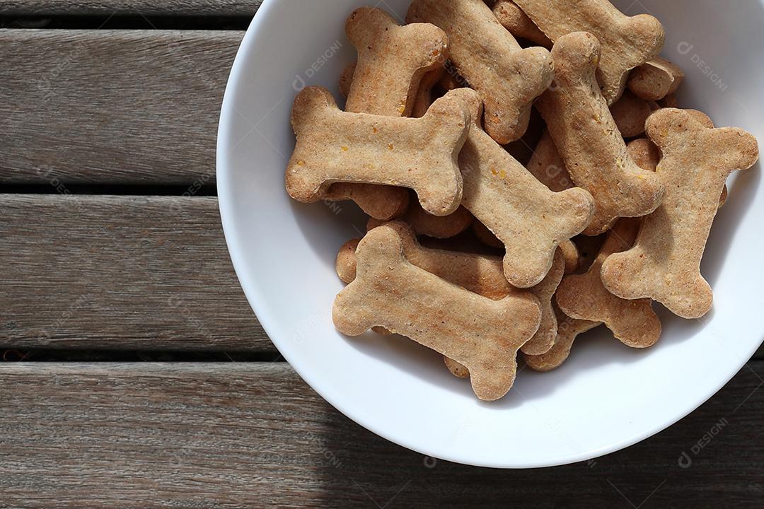 comida de cachorro seca em uma tigela na vista superior de fundo de madeira.