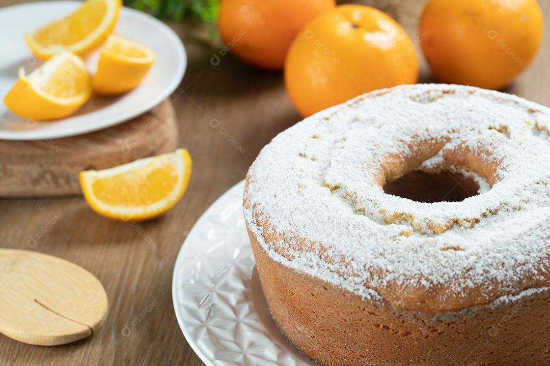 Bolo úmido de frutas laranja no prato com fatias de laranja na mesa de madeira. Delicioso café da manhã, hora do chá tradicional inglês. Receita de bolo de laranja.