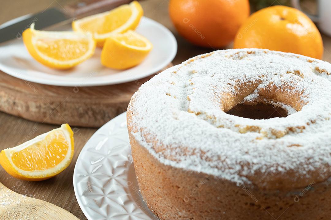 Bolo úmido de frutas laranja no prato com fatias de laranja na mesa de madeira. Delicioso café da manhã, hora do chá tradicional inglês. Receita de bolo de laranja.