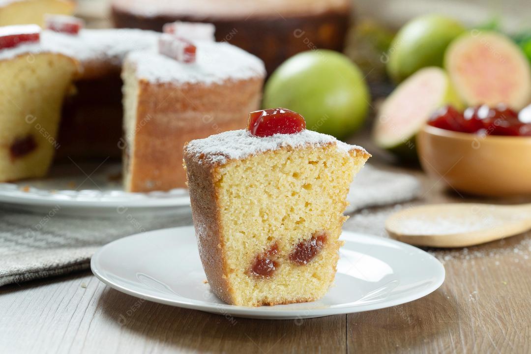 Pedaço de bolo de milho brasileiro feito com um tipo de farinha de milho (Fuba) recheado com goiabada. Em uma mesa de festa de madeira. Doces típicos da festa junina. bolo de fubá