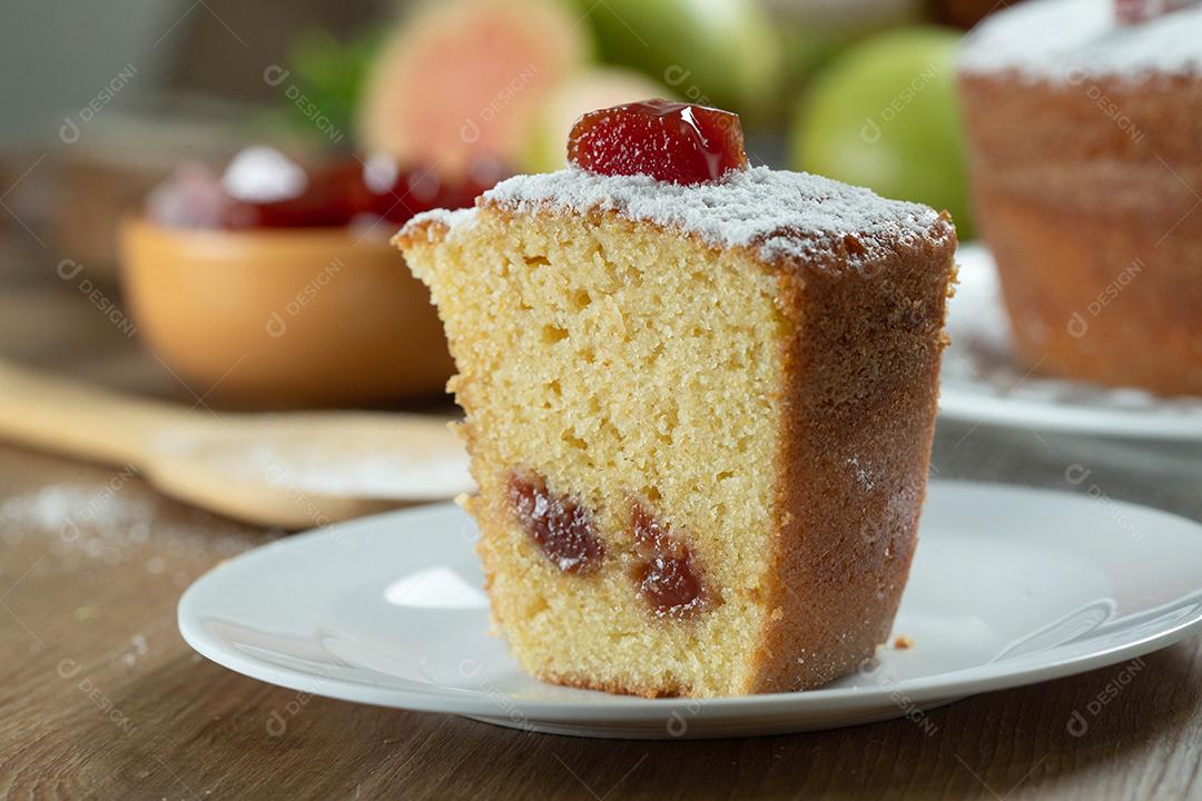 Piece of Brazilian corn cake made with a type of corn flour (Fuba) stuffed with guava. On a wooden party table. Typical sweets of the Festa Junina. cornmeal cake