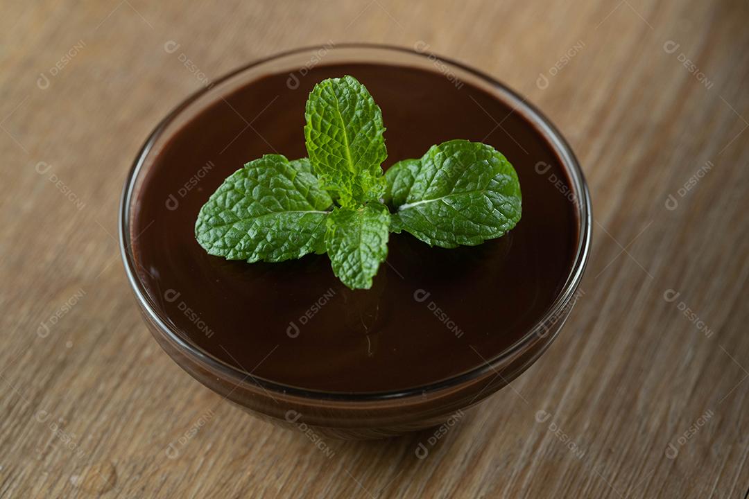 mousse de molho de chocolate com hortelã em frasco de vidro na mesa de madeira