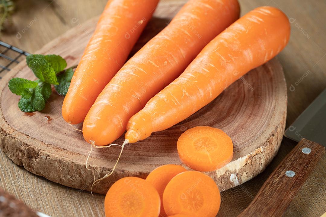 Cenouras frescas e hortelã em uma mesa de madeira.