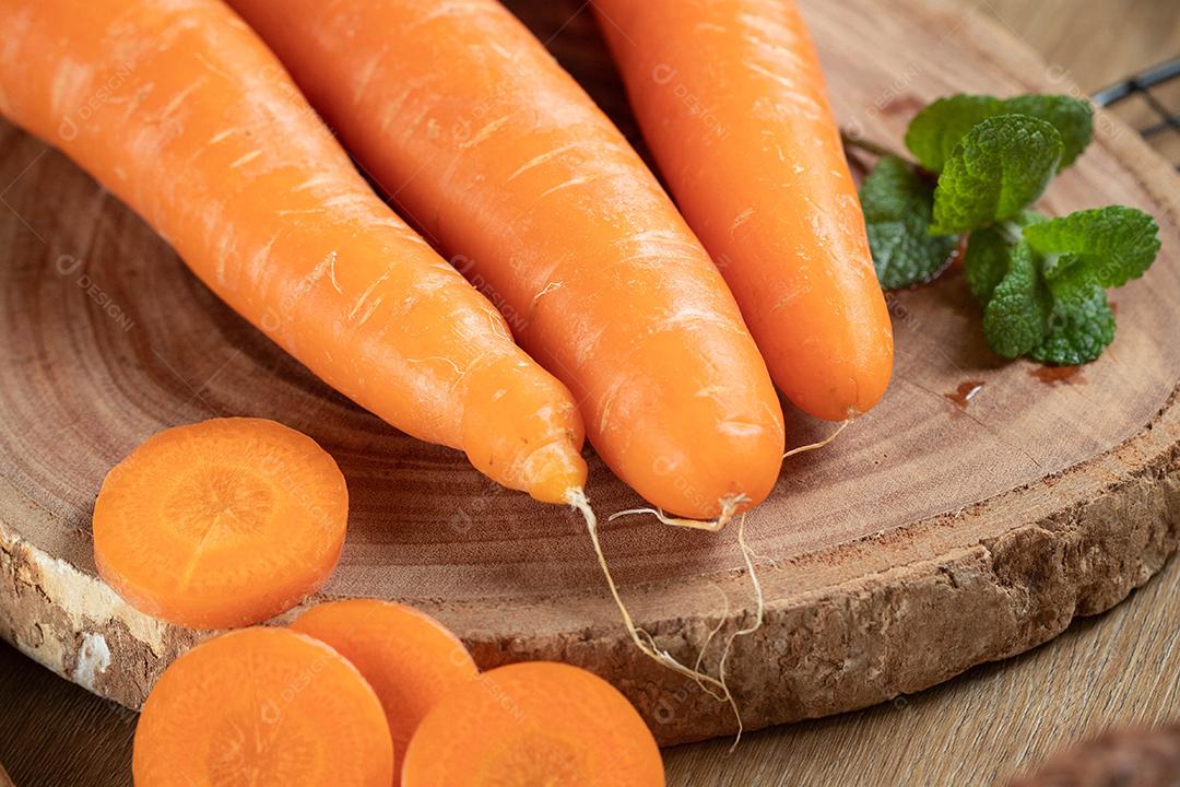 Cenouras frescas e hortelã em uma mesa de madeira.