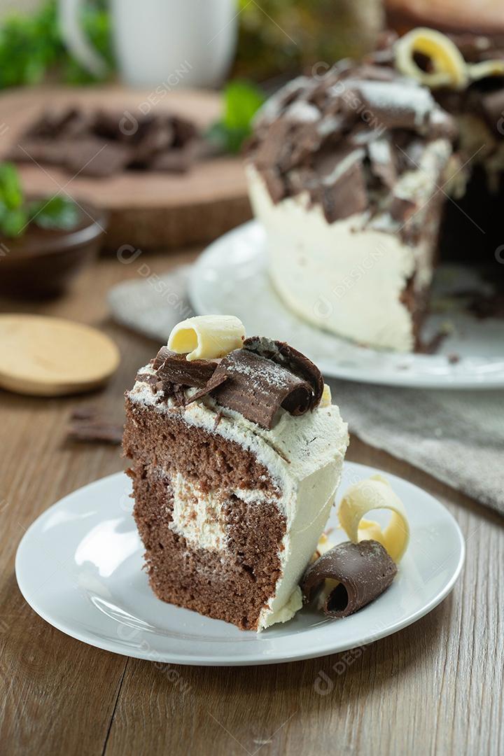 Feche o pedaço de chocolate branco e bolo de chocolate escuro dois amores na mesa de madeira. Bolo de aniversário e casamento.