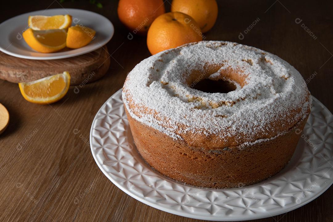 Bolo úmido de frutas laranja no prato com fatias de laranja na mesa de madeira. Delicioso café da manhã, hora do chá tradicional inglês. Receita de bolo de laranja.