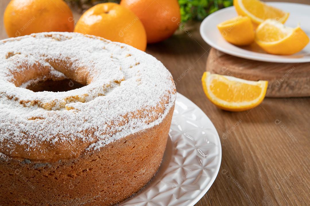 Bolo úmido de frutas laranja no prato com fatias de laranja na mesa de madeira. Delicioso café da manhã, hora do chá tradicional inglês. Receita de bolo de laranja.
