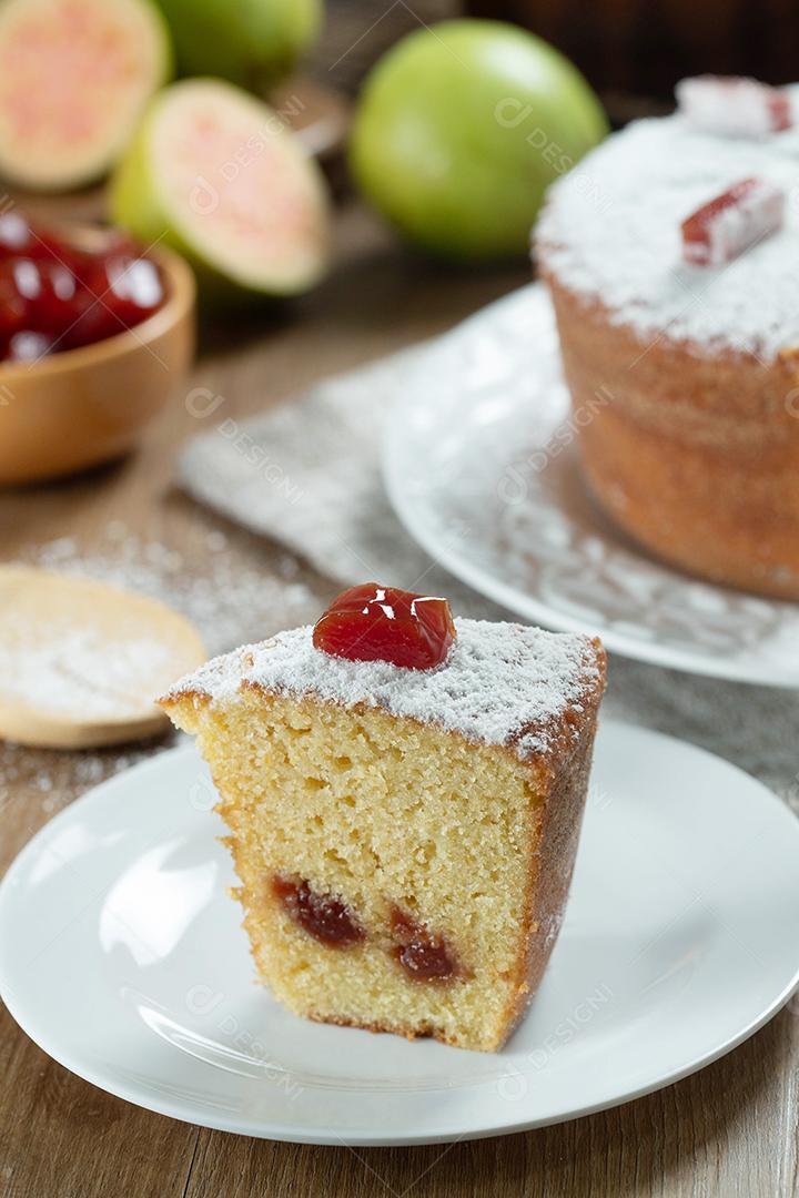 Feche o pedaço de bolo de milho brasileiro feito com um tipo de farinha de milho (Fuba) recheada com goiabada. Em uma mesa de festa de madeira. Doces típicos da festa junina.