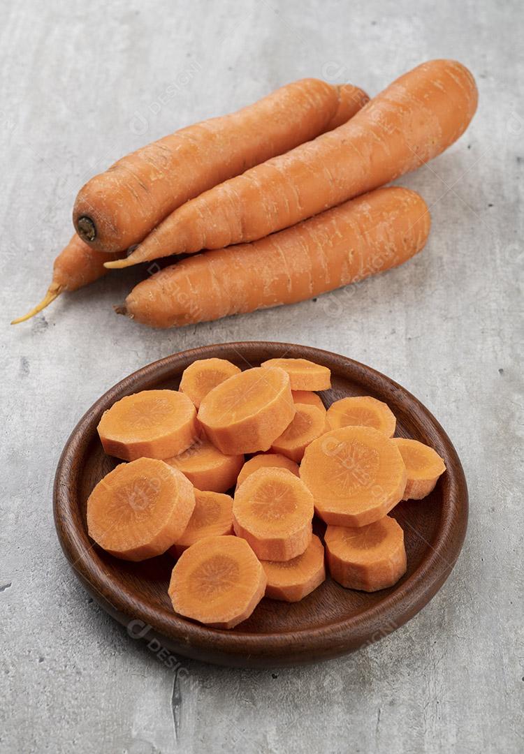 Cenouras e fatias em um prato sobre fundo cinza rústico.