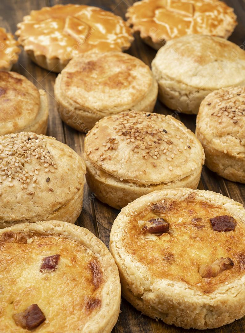 Tortas caseiras variadas e quiches sobre a mesa de madeira.