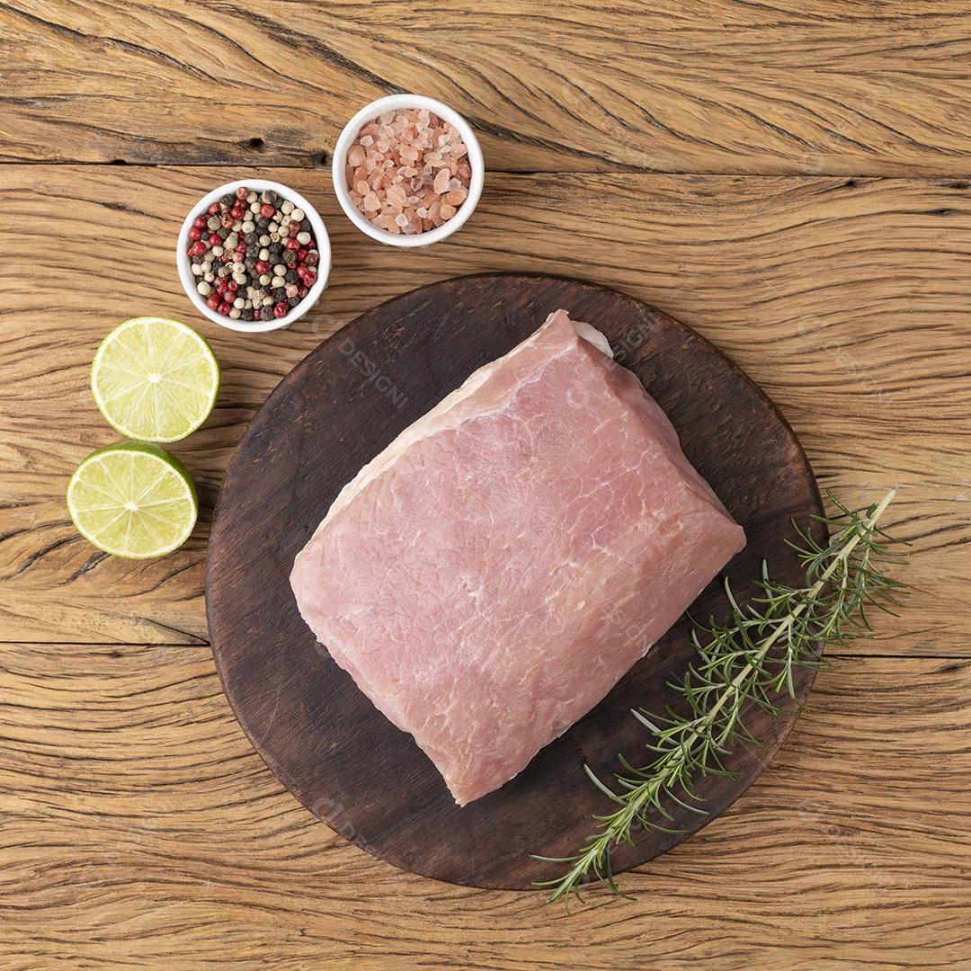 Carne de lombo de porco crua sobre tábua de madeira com temperos.