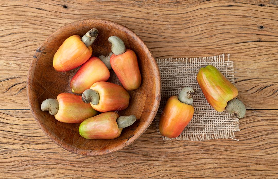 Um grupo de cajus em uma tigela sobre a mesa de madeira.