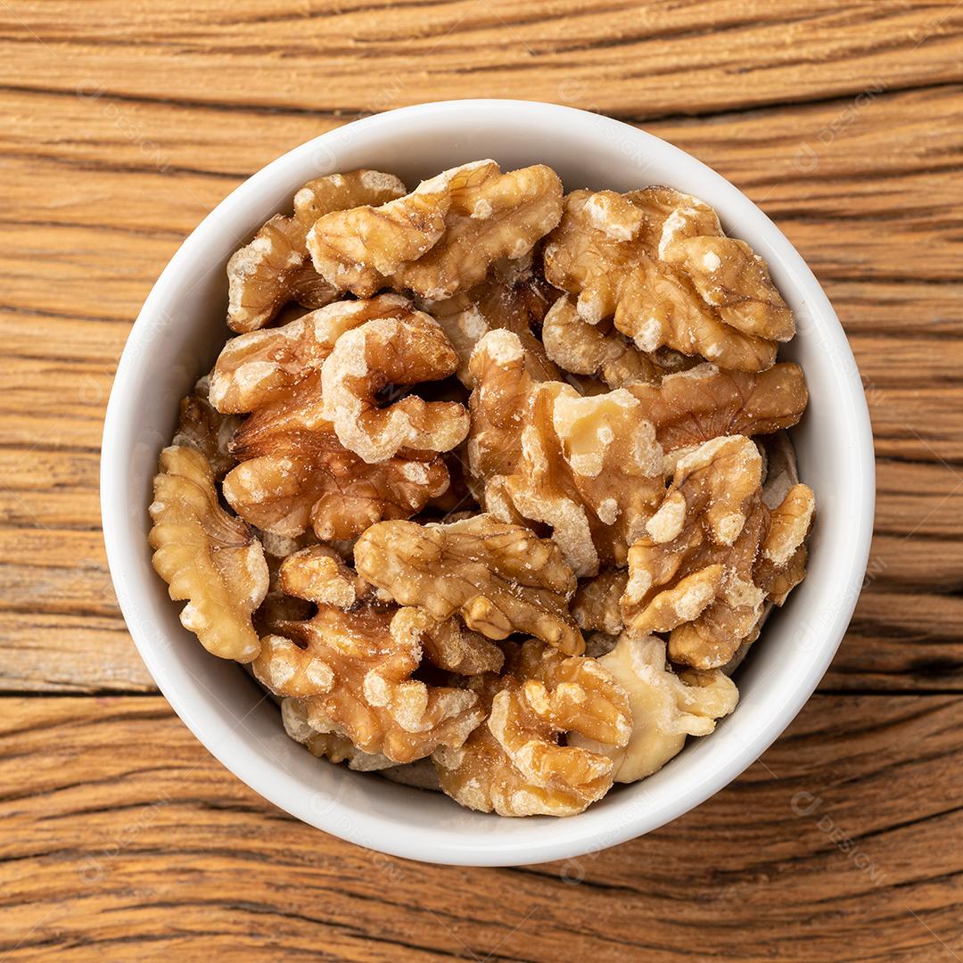 Nozes em uma tigela sobre a mesa de madeira.