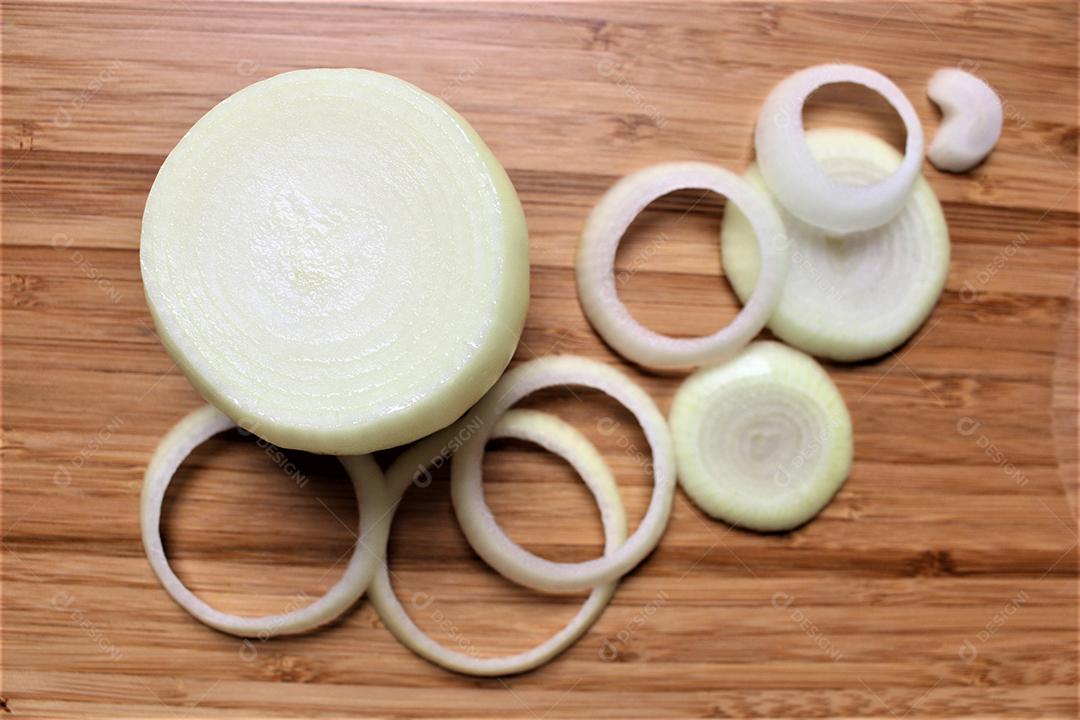 Cebolas cortadas em rodelas sobre uma mesa de madeira