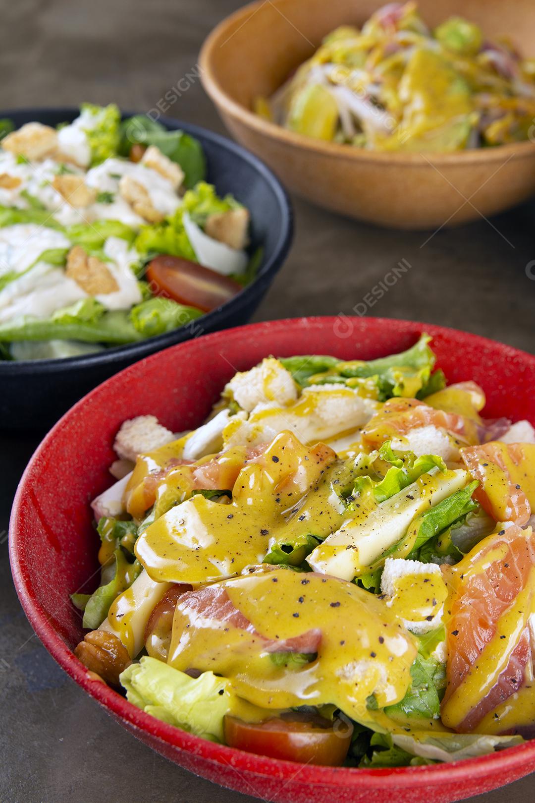 Saladas em tigelas coloridas sobre fundo de pedra