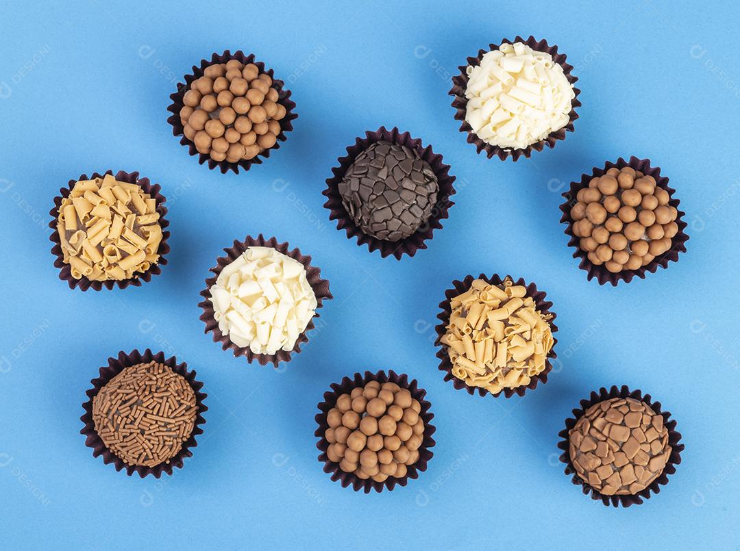 Brigadeiros típicos brasileiros, vários sabores sobre fundo colorido.