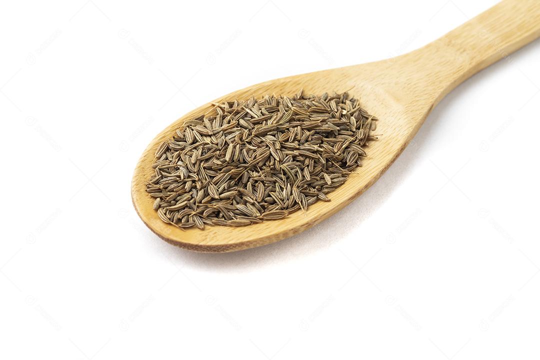 Sementes de cominho em uma colher de pau isolada sobre fundo branco.