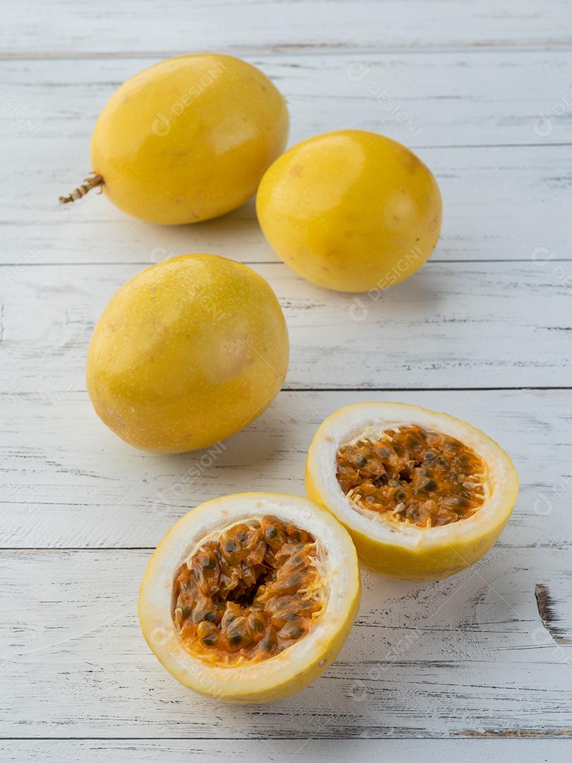 Maracujás com frutas cortadas sobre a mesa de madeira.