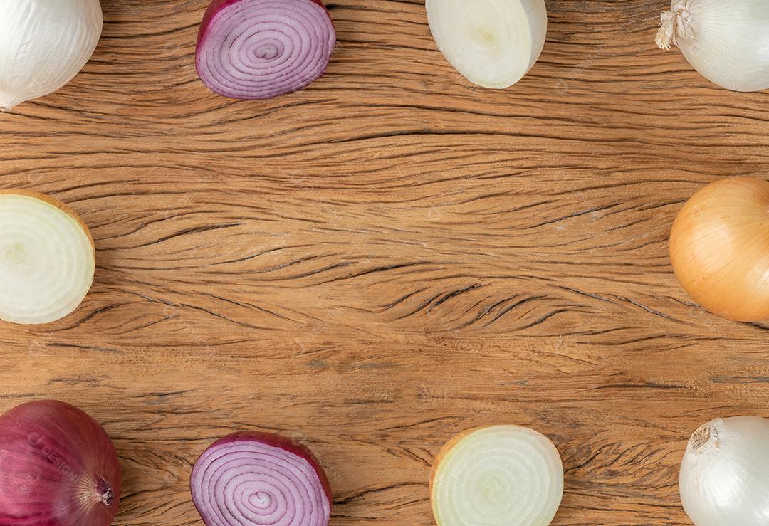 Cebolas variadas com metades sobre mesa de madeira com espaço de cópia.