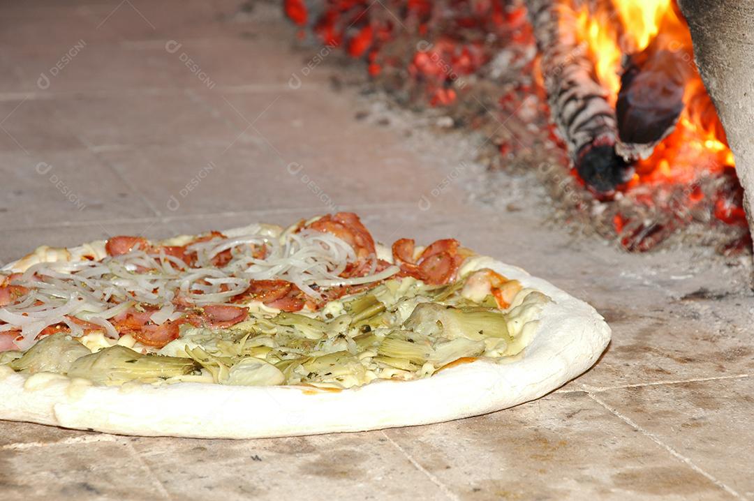 PIzza crua indo para fornalha para ser assada para ser vendida