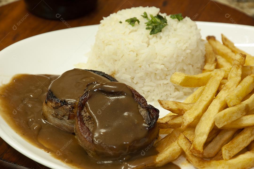 Plate of food on a wooden table rice and french fries