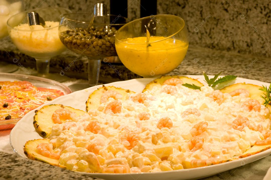 Camarão cremoso em bandeja branca sobre mesa de pedra