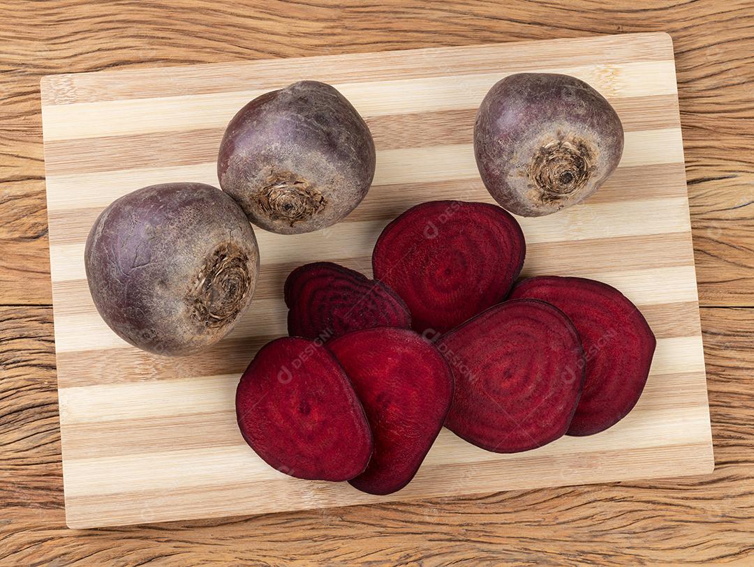 Beterrabas cruas com fatias em uma mesa de madeira.