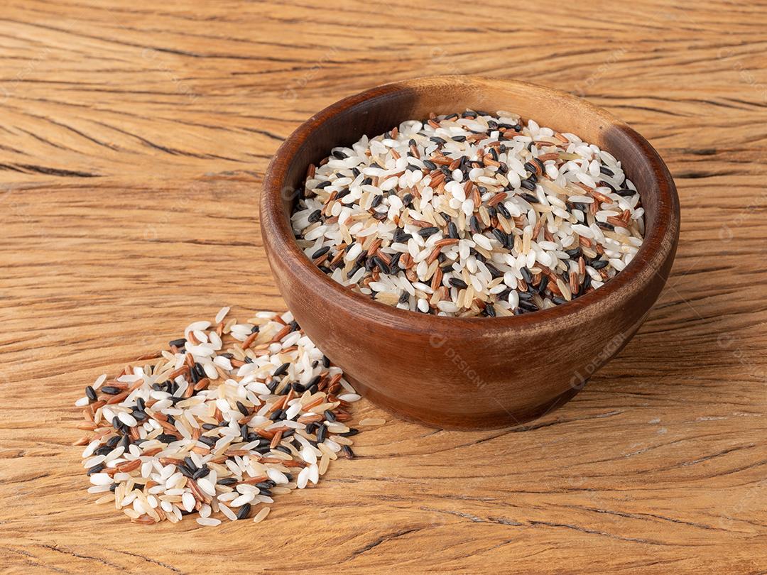 Arroz sortido cru em uma tigela sobre a mesa de madeira.